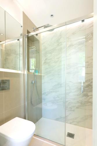 a bathroom with a glass shower with a toilet at Haus of Timon Victorian Elegance near Olympia in London