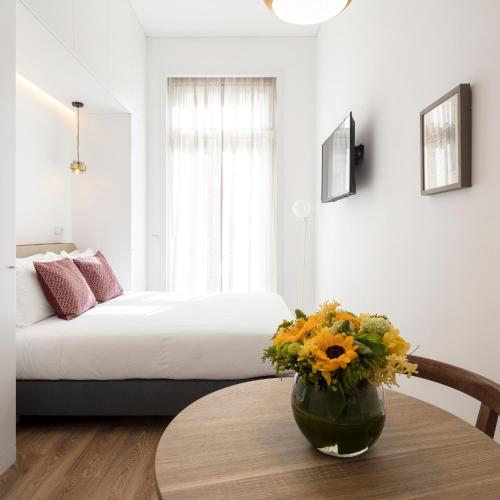 a room with a bed and a table with a vase of flowers at LSA Chiado Emenda by Numa in Lisbon