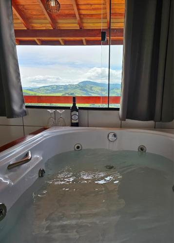 a bath tub with a bottle of wine in front of a window at Oasis na montanha in Bueno Brandão