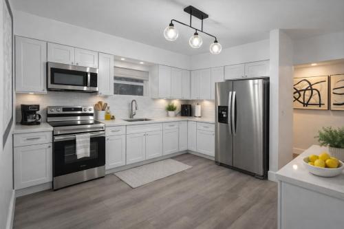 a kitchen with white cabinets and a stainless steel refrigerator at Fort Lauderdale Airport Bleu Lagunna in Hollywood