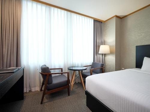 a hotel room with a bed and a table and chairs at 퀸벨호텔 in Tōson