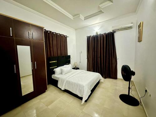 a bedroom with a white bed and a black chair at Resmay apartment in Abuja