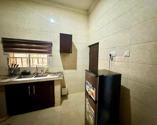 a kitchen with a black refrigerator and a sink at Resmay apartment in Abuja