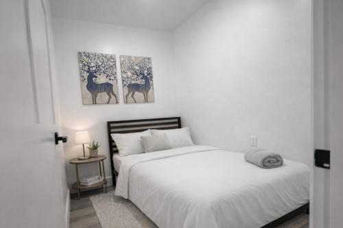 a white bedroom with a bed and two paintings on the wall at Fort Lauderdale Airport Bleu Lagunna in Hollywood