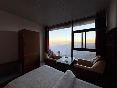 a room with a bed and a table and a window at Valley View in Dhanaulti