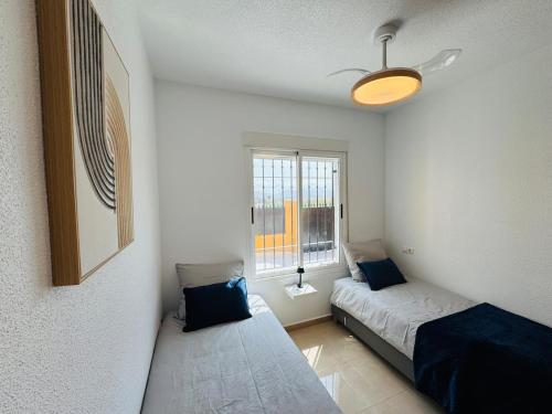 a small room with two beds and a window at Casa Indigo Mazarron in Mazarrón