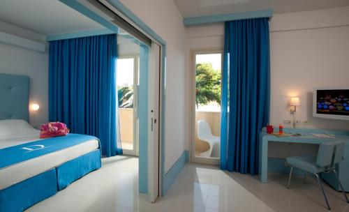 a bedroom with blue curtains and a desk and a bed at Domina Zagarella Sicily in Santa Flavia