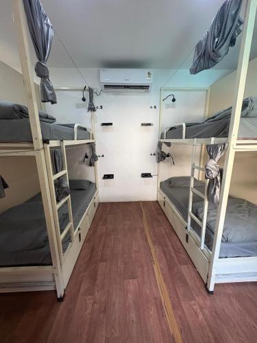 two bunk beds in a room with wooden floors at Simple Belle Stay ,Pool &Bar in Vagator