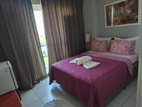 a bedroom with two beds with purple sheets and a window at Rio Stay Suíte in Rio de Janeiro