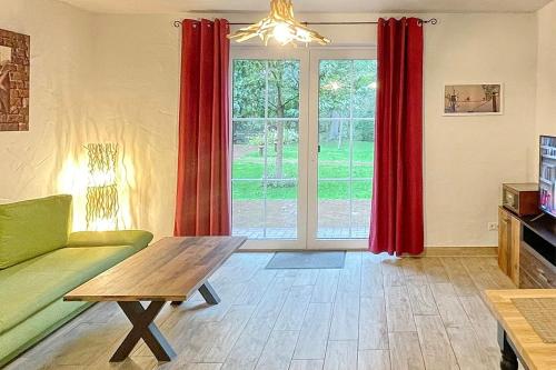 a living room with a green couch and red curtains at Holzfäller Baum 2 in Burg