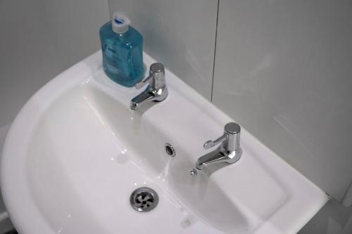 a white sink with a blue bottle on top of it at Private Studio Apartment · Quiet · Sleeps 2 in Nottingham