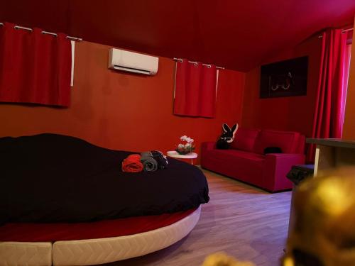 a bedroom with red walls and a bed and a couch at Love Room- Jacuzzi XXL- Climatisé- Table massage Accessoires in LʼEscarène