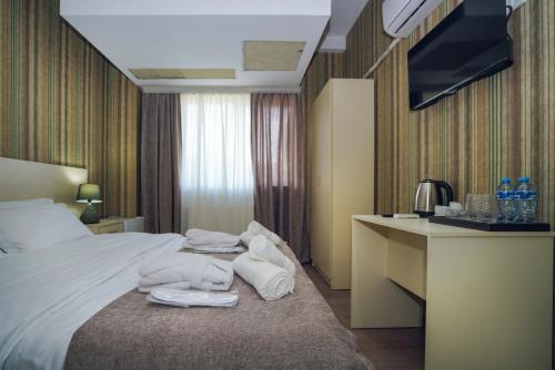 a hotel room with towels on a bed and a desk at Sport time Hotel & Spa in Tbilisi City