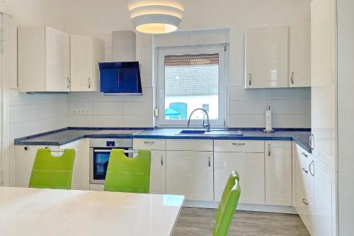 a kitchen with white cabinets and green chairs at Malve in Lübbenau