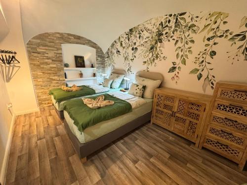 a bedroom with two beds and a wall with leaves at Tessa Central House in Kőszeg