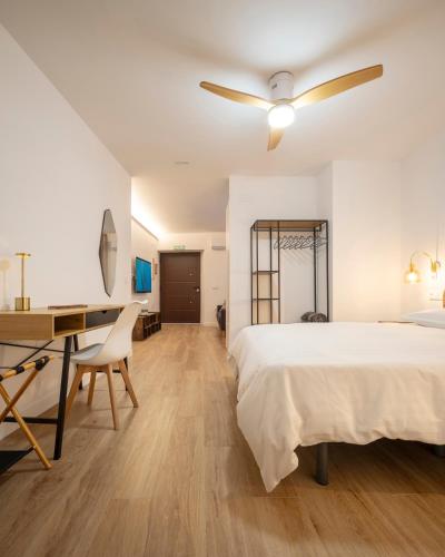 a bedroom with a bed and a desk and a ceiling fan at Apartamento Donoso Cortés in Badajoz