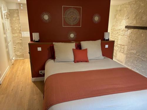a bedroom with a bed with red and white pillows at gite 3 le havre in Aubeterre-sur-Dronne