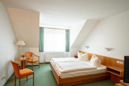 a bedroom with a bed and a chair and a television at Pension Seeluft in Ahrenshoop