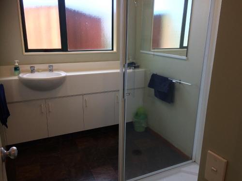 a bathroom with a sink and a glass shower door at Cedar Chalets in Methven