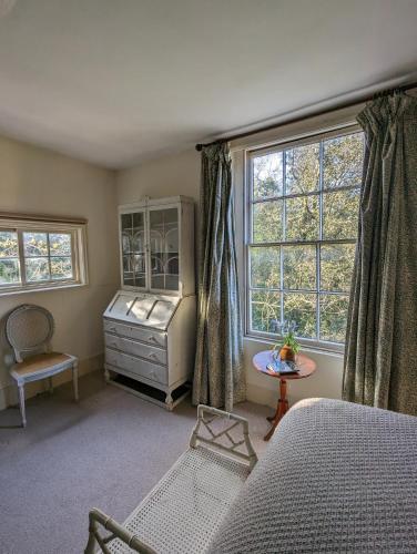 a bedroom with a bed and a dresser and two windows at Old Manor House in Shepperton