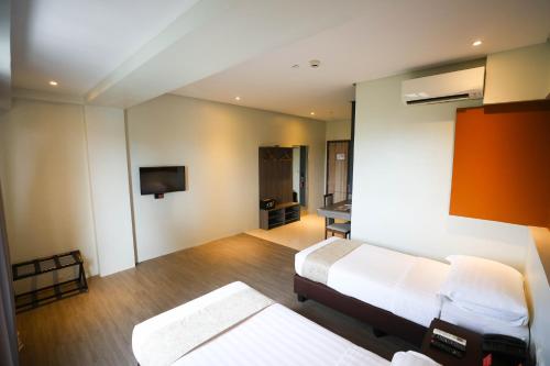 a bedroom with two beds and a tv on the wall at PROXY by The Oriental Albay in Legazpi