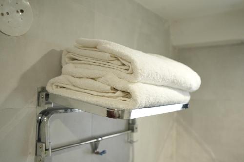 a pile of towels on a towel rack in a bathroom at Hotel Elite Executive Lodging in Bārāmati
