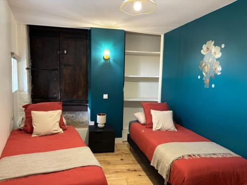 two beds in a room with blue and red at gite 4 le refuge in Aubeterre-sur-Dronne