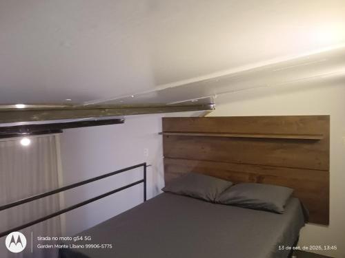 a small bedroom with a bed with a wooden headboard at Flat no Garden 2 in Rondonópolis