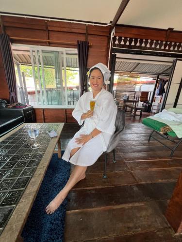 a woman sitting in a chair holding a drink at Ruen Rinna home stays in Surin