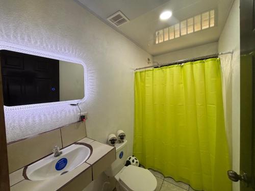 ein Badezimmer mit grünem Duschvorhang und Waschbecken in der Unterkunft Izzy Blue House in Talamanca
