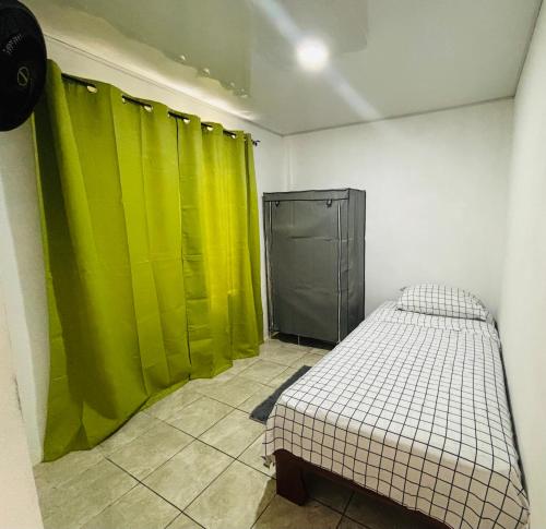 ein Zimmer mit grünen Vorhängen und einem Bett darin in der Unterkunft Izzy Blue House in Talamanca