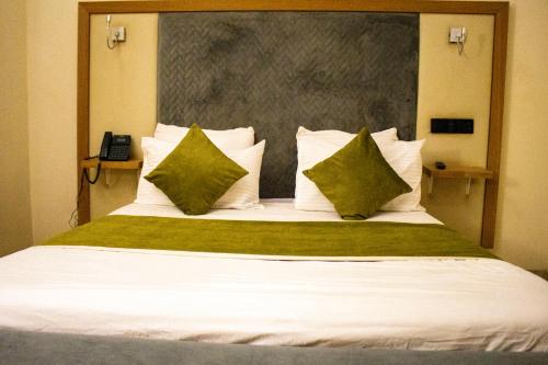 a bedroom with a large bed with green and white pillows at Résidence PLAZZAET OUAGA 2000 in Ouagadougou