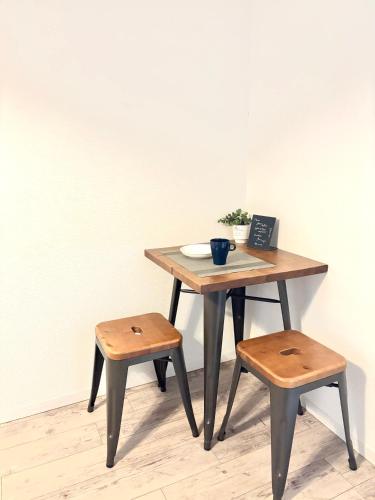 a wooden table with two stools and a table with a laptop at Guest House Re-worth Yabacho1 302 in Nagoya