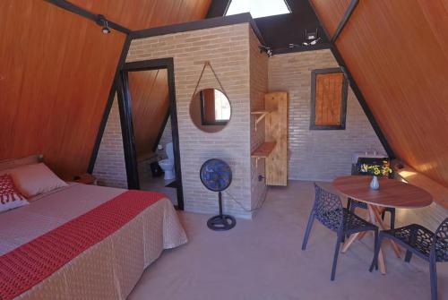 a bedroom with a bed and a table and chairs at Chalés Vale da Luma in Cavalcante