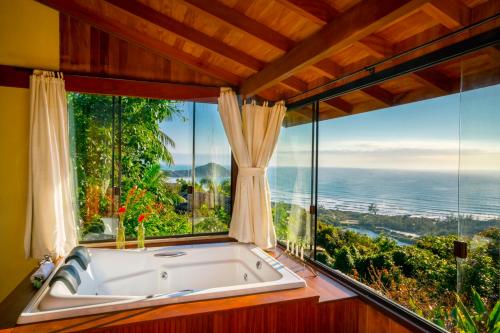 bañera en una habitación con ventana grande en Pousada Caminho do Rei, en Praia do Rosa