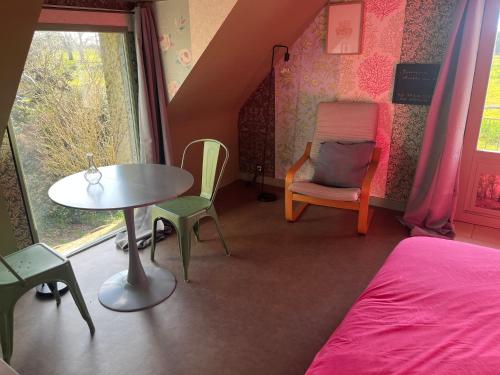 a bedroom with a bed and a table and chairs at Escapade de charme à Questembert in Questembert