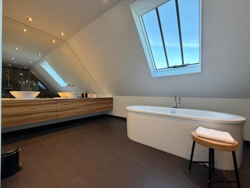 a bathroom with a large white tub and a window at B&B Louwi in Breugel