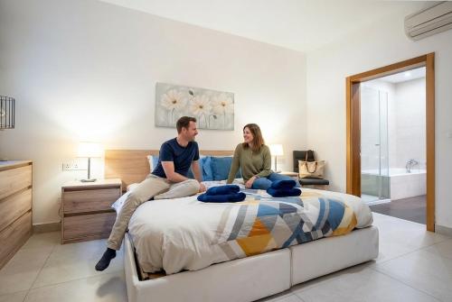 a man and woman sitting on a bed at The Strand Waterfront Apartment with 3 Bedrooms, 4 Bathrooms, Private Garage in Sliema