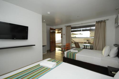 a hotel room with two beds and a flat screen tv at Bluewaves Westcliff Villa in Boracay