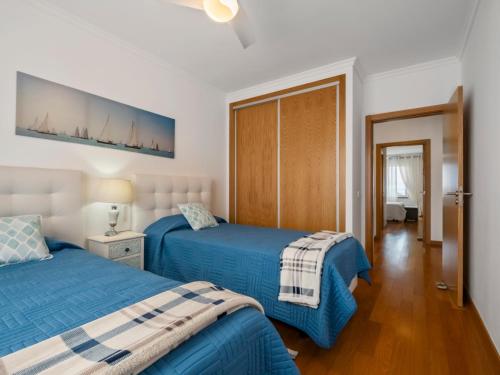 two beds in a bedroom with blue sheets at Tamariz Flat in Santa Cruz