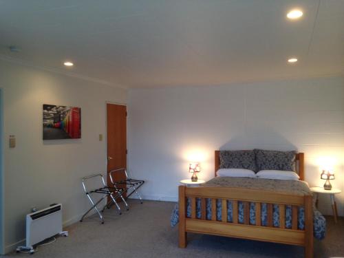 a bedroom with a bed and two chairs in it at Affordable On Arun in Oamaru