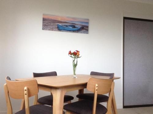 a dining room table with chairs and a vase of flowers at Affordable On Arun in Oamaru