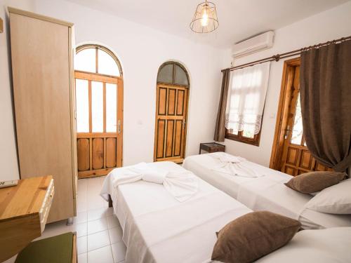 two beds in a room with two windows at Old Kalamaki Pansiyon in Kalkan