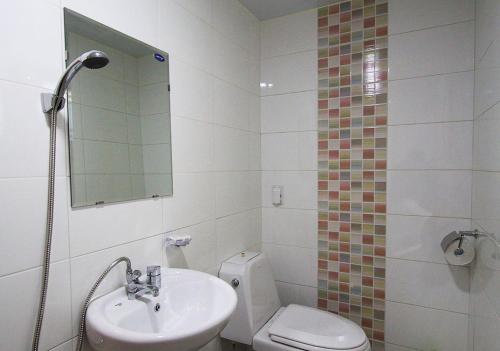 a bathroom with a sink and a toilet and a mirror at Dorandoran Guesthouse in Gyeongju