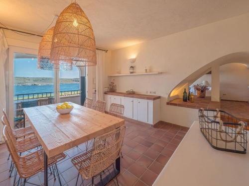 a kitchen and dining room with a table and a view of the ocean at Els Tamarells Apartment by 3VILLAS in Fornells
