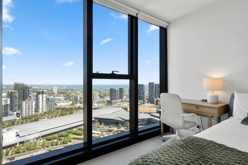 a bedroom with a bed and a desk and a window at 39th floor luxurious spacious apartment in Melbourne