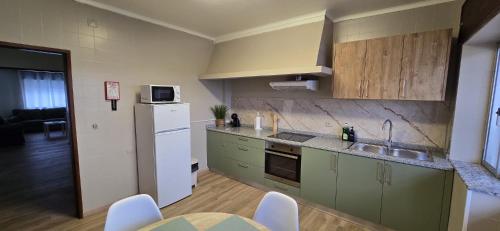 a kitchen with green cabinets and a white refrigerator at Apartamento Vila Melgaço in Melgaço