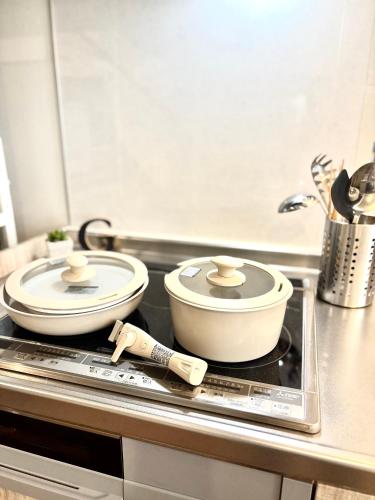 two pots and pans sitting on a stove in a kitchen at Guest House Re-worth Yabacho1 202 in Nagoya
