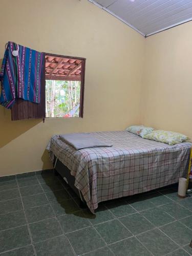 a bedroom with a bed in a room with a window at Casa oblíqua no Vale do Capão in Palmeiras