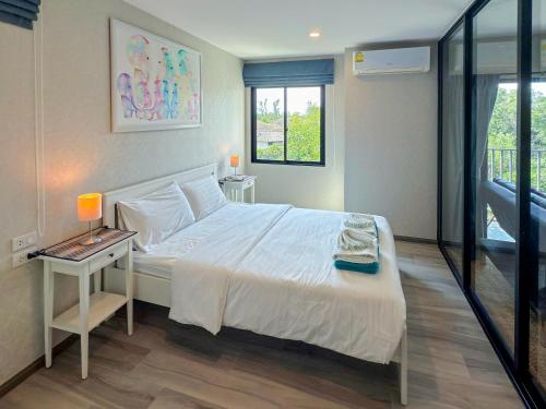 a bedroom with a bed and a table with a lamp at The Title Residencies Naiyang F by Mill in Nai Yang Beach